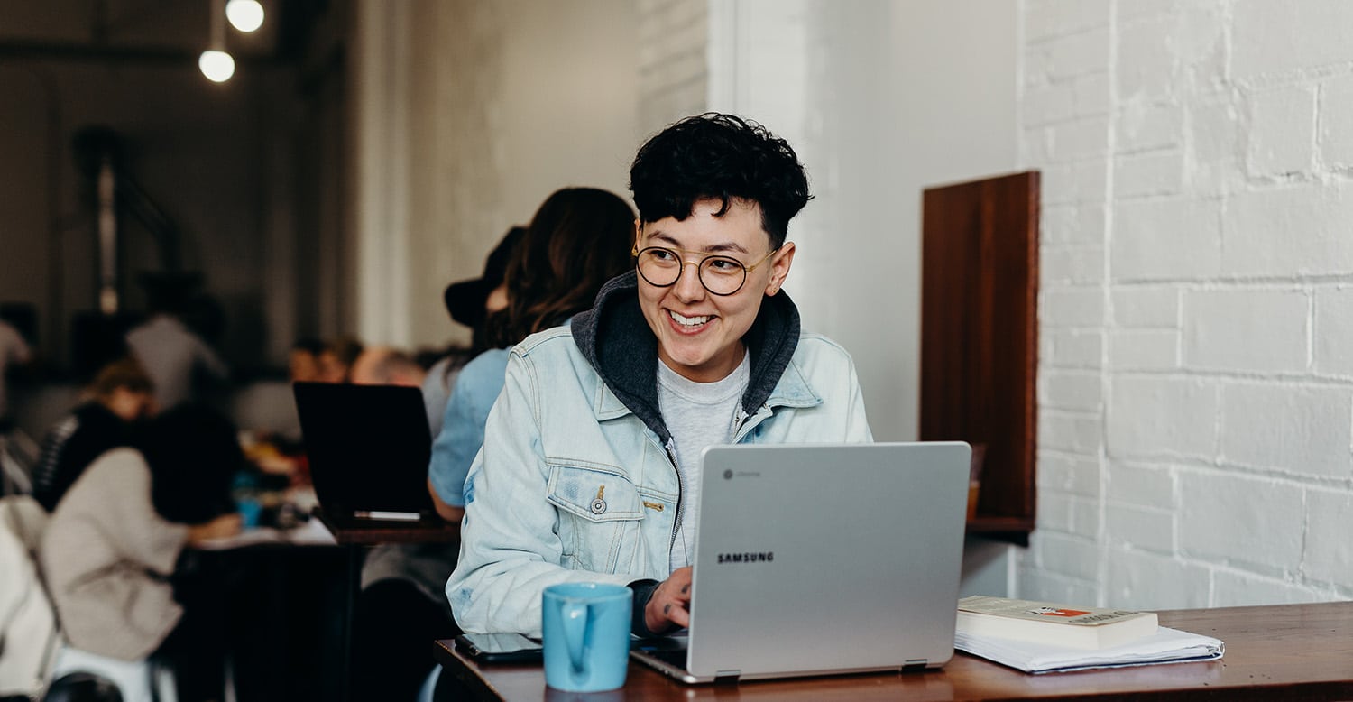 Image of a person using their laptop and smiling.