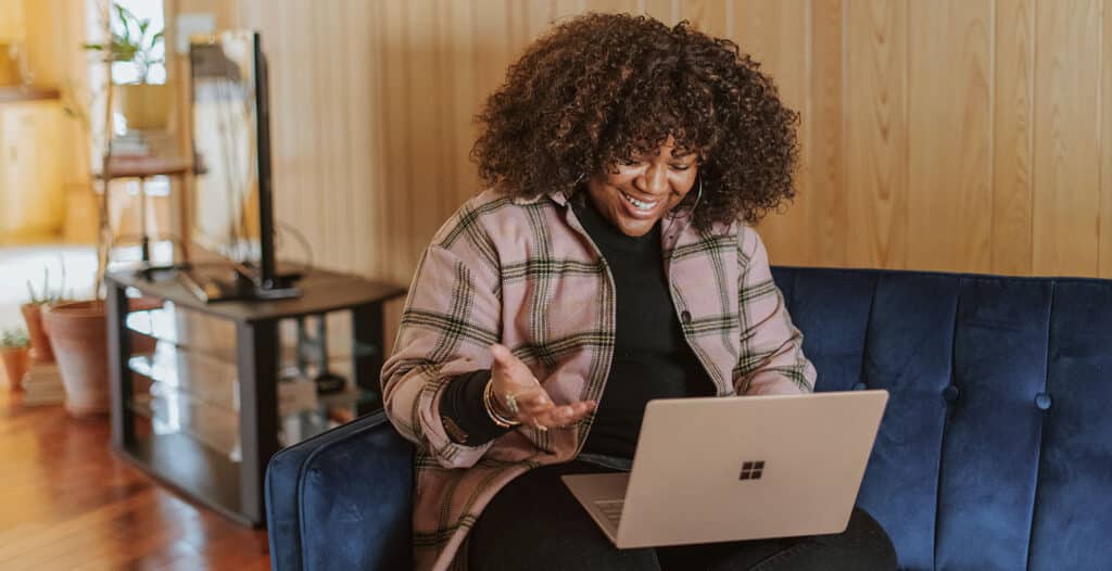 Image of a woman smiling and looking at her laptop.