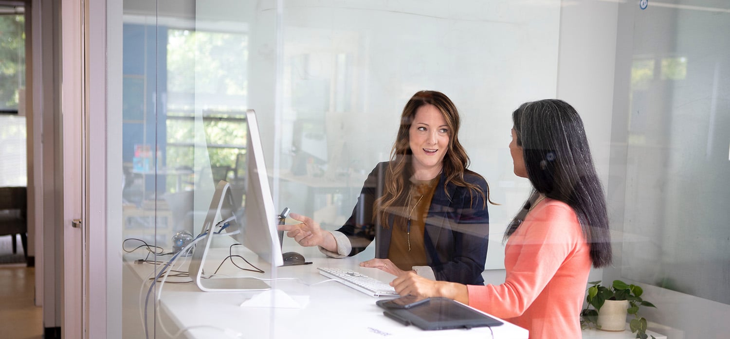 Image of two women working together at a desk space.