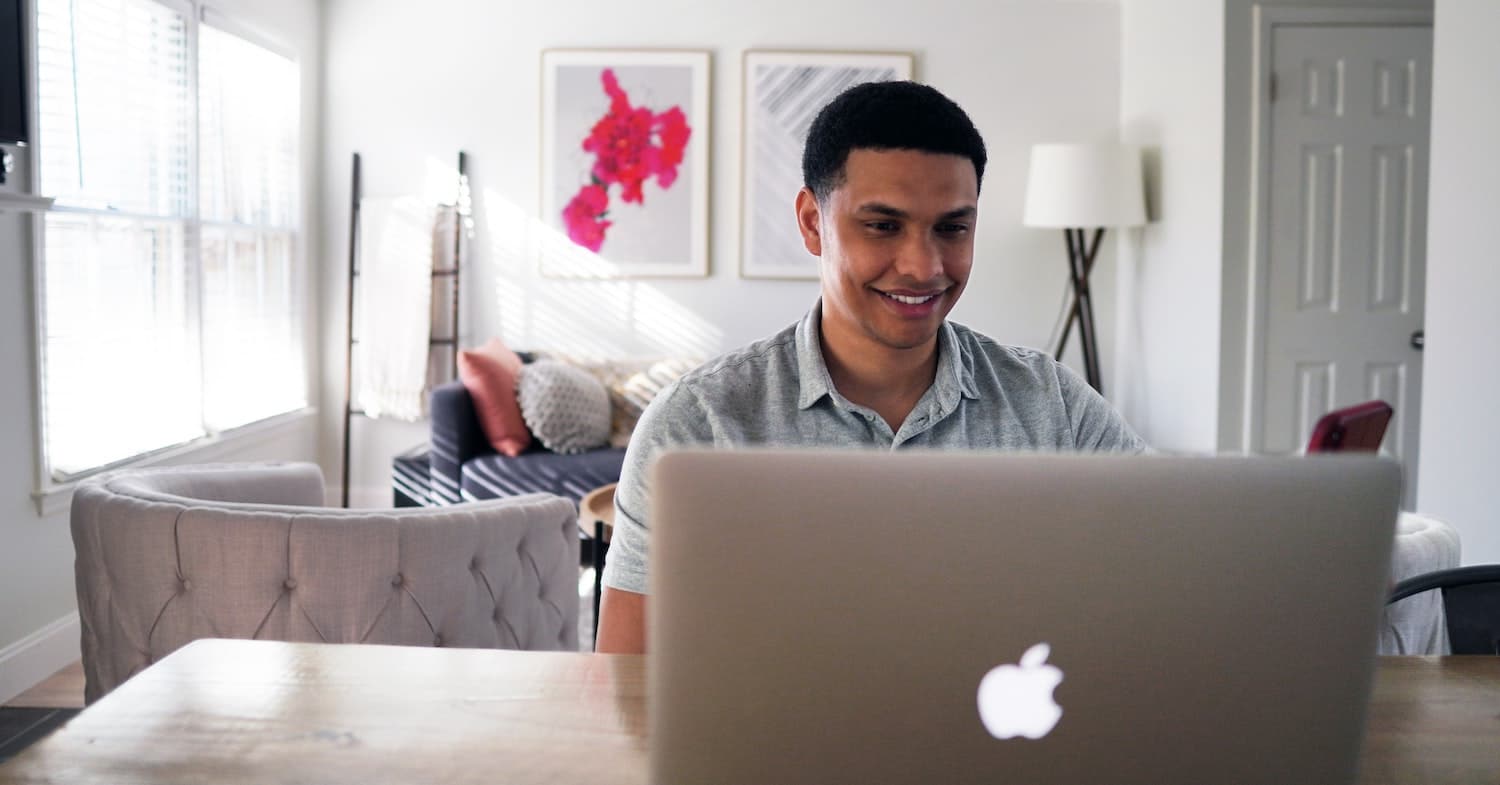 Image of student looking at their laptop and smiling.