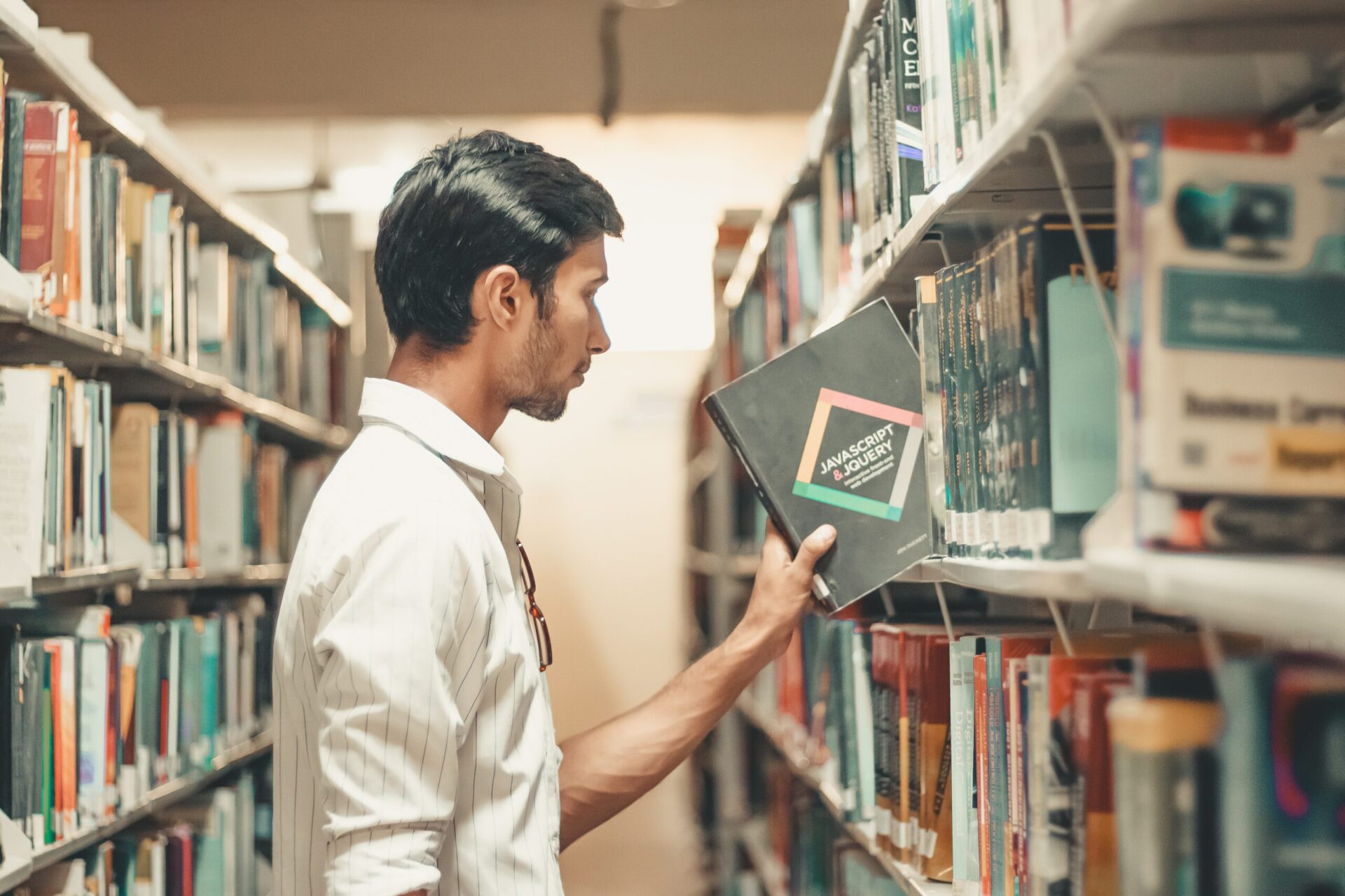 Man pullling a book off the shelf at a library