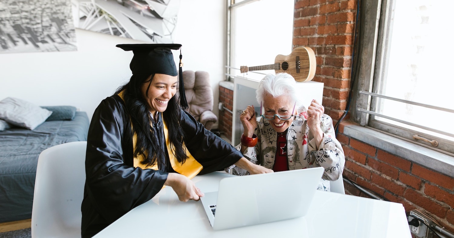 Image of a graduating student and her grandmother watching a graduation ceremony on a laptop.