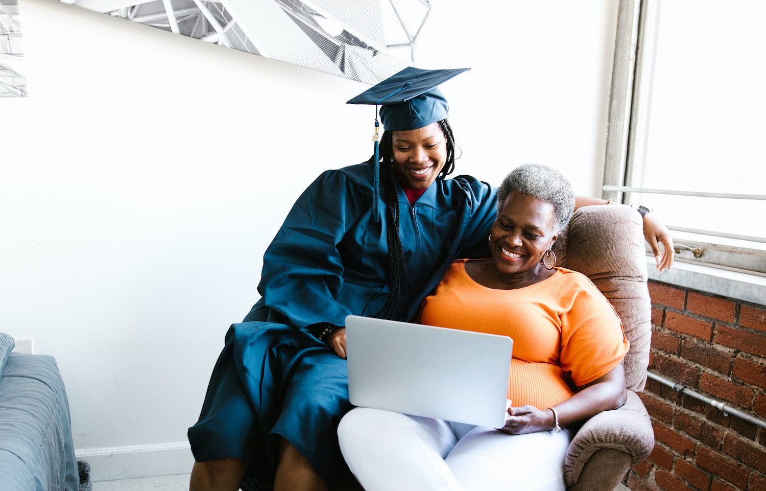 Image of a student graduate and family member watching a graduation ceremony on their laptop.