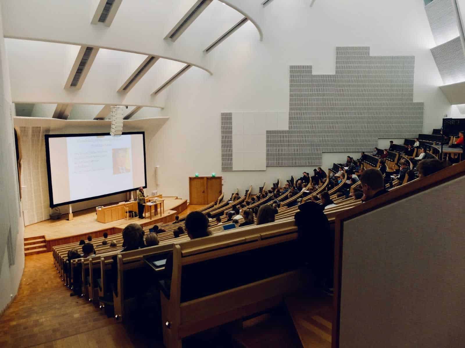 auditorium with people listening to a lecturer at the front