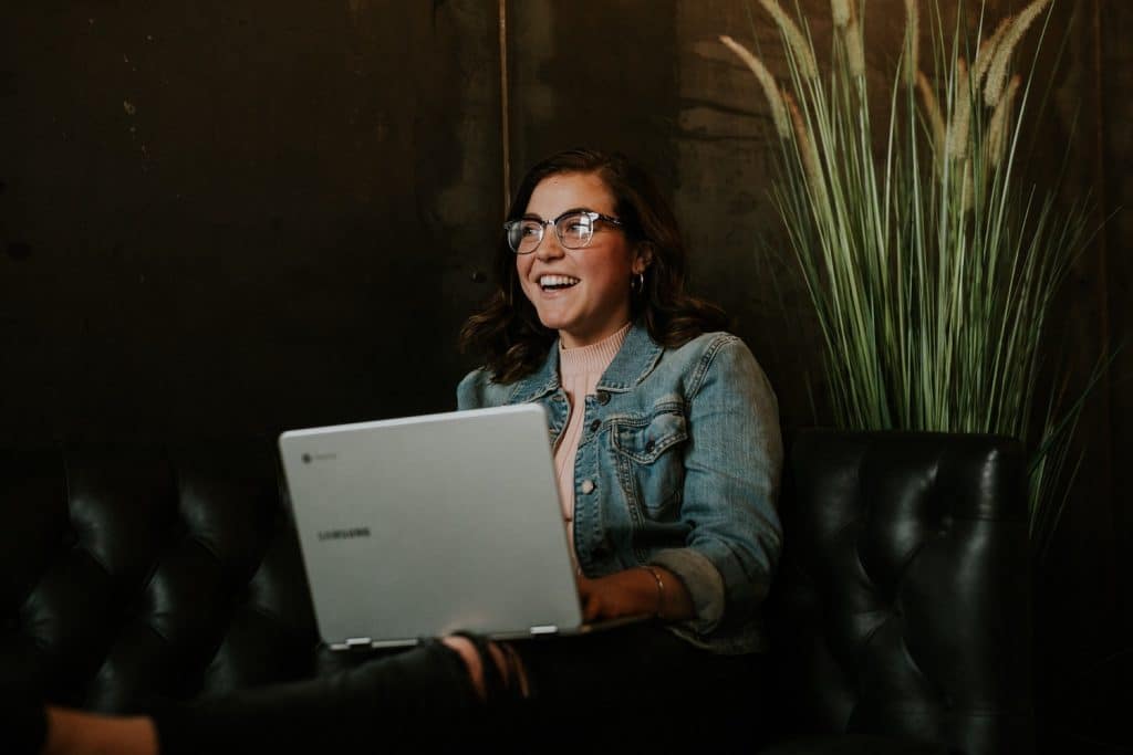 Image of a young woman smiling while using a laptop.