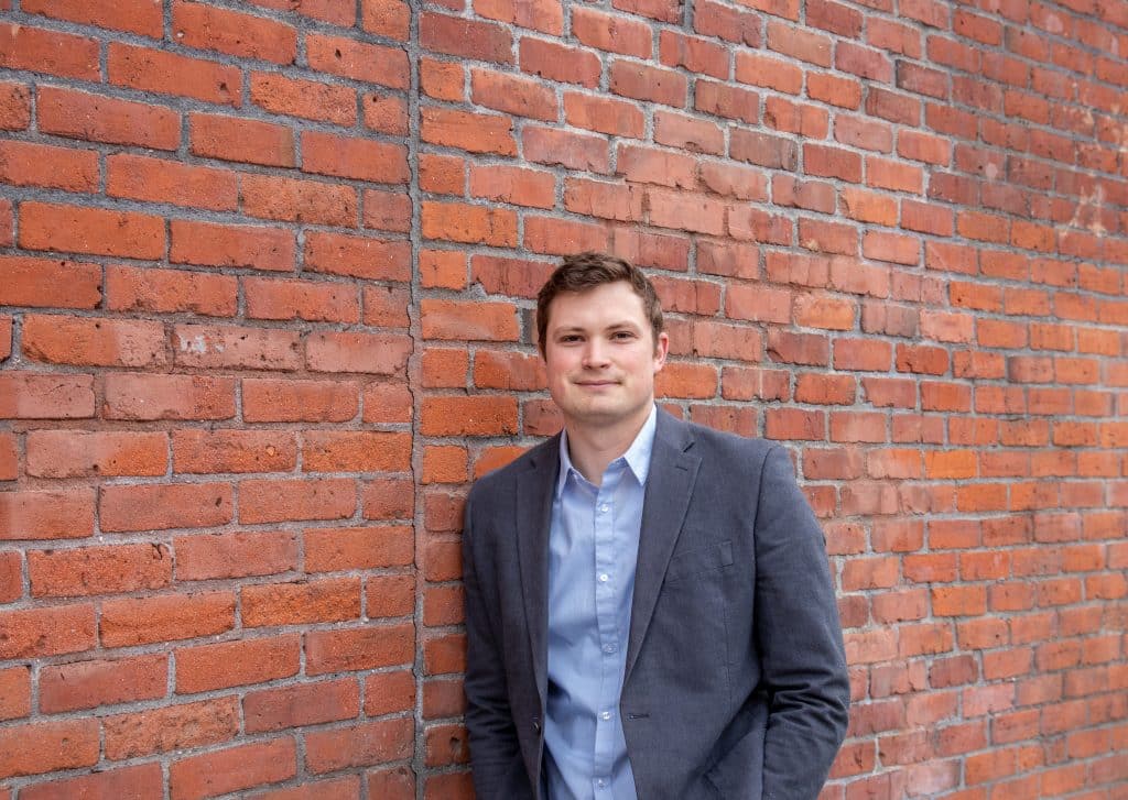 Man in business clothes standing in front of a brick wall