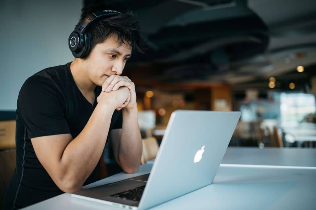 man wearing headphones working on his laptop on a table