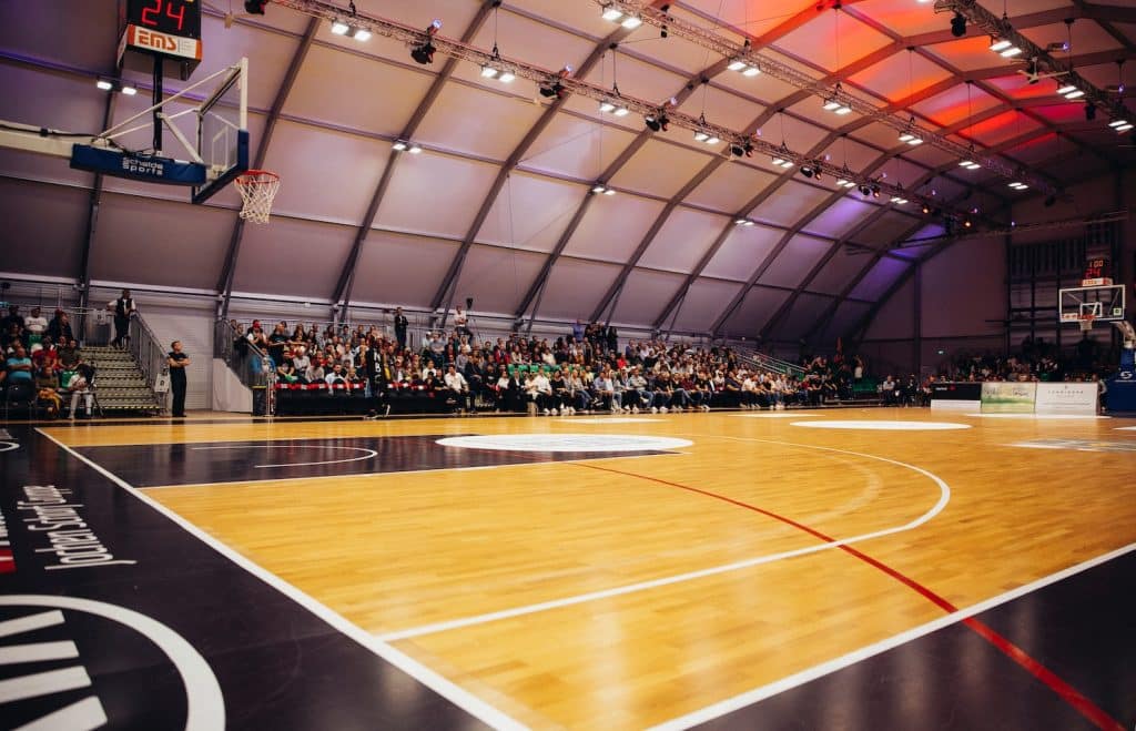 Image of a basketball stadium with audience members sitting around it.