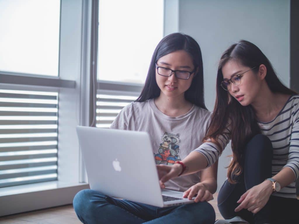 Image of two women looking at something on their laptop screen.