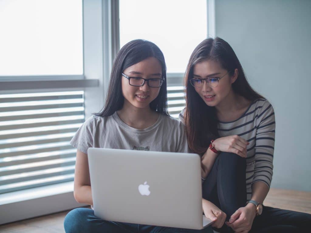 Image of two students looking at a laptop screen.
