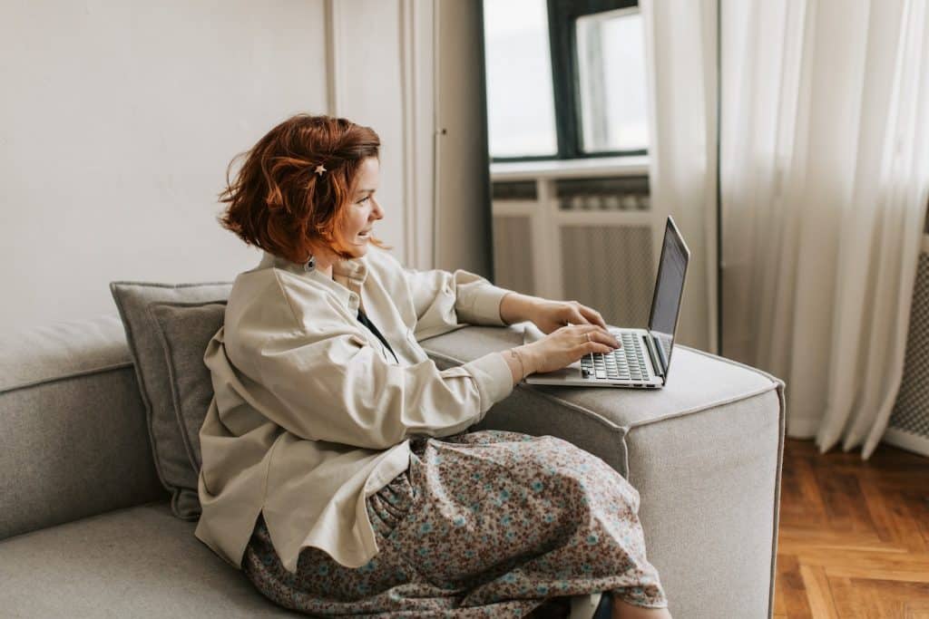 Image of a young woman typing on a laptop while sitting on a couch.