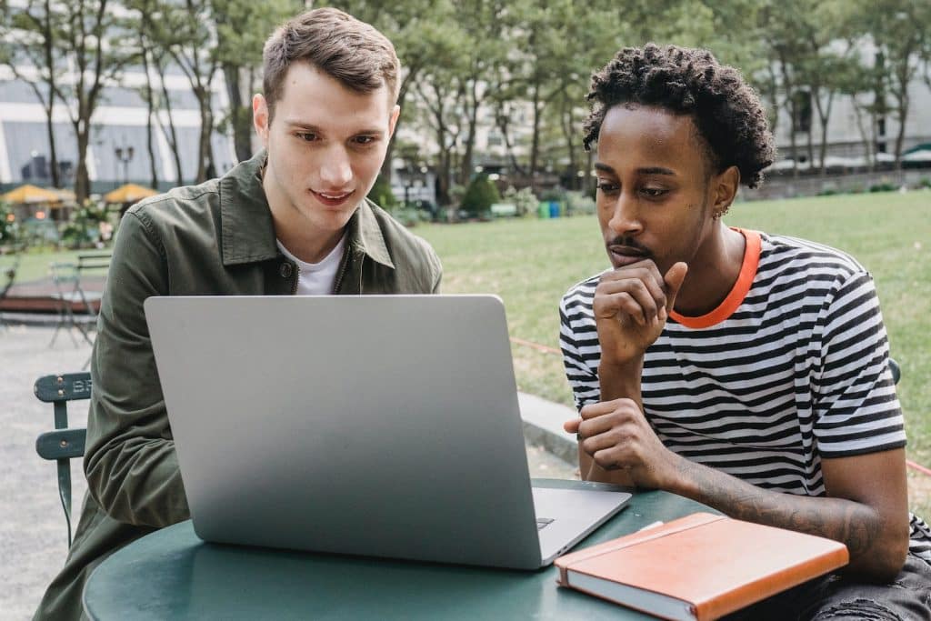 Image of two young men looking at a laptop together.