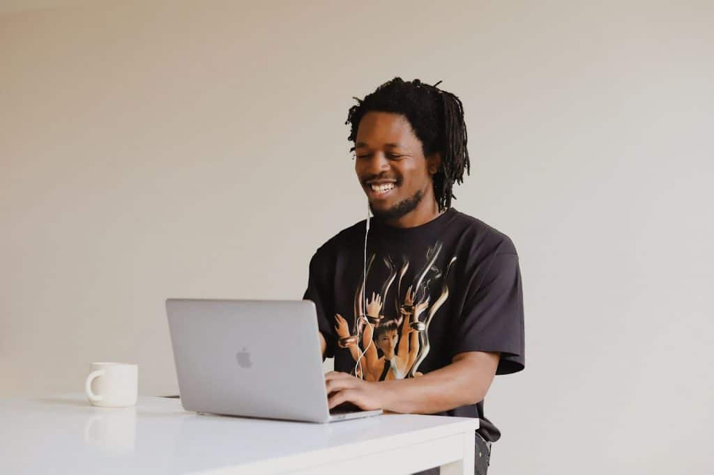 smiling man working on his laptop on a white table