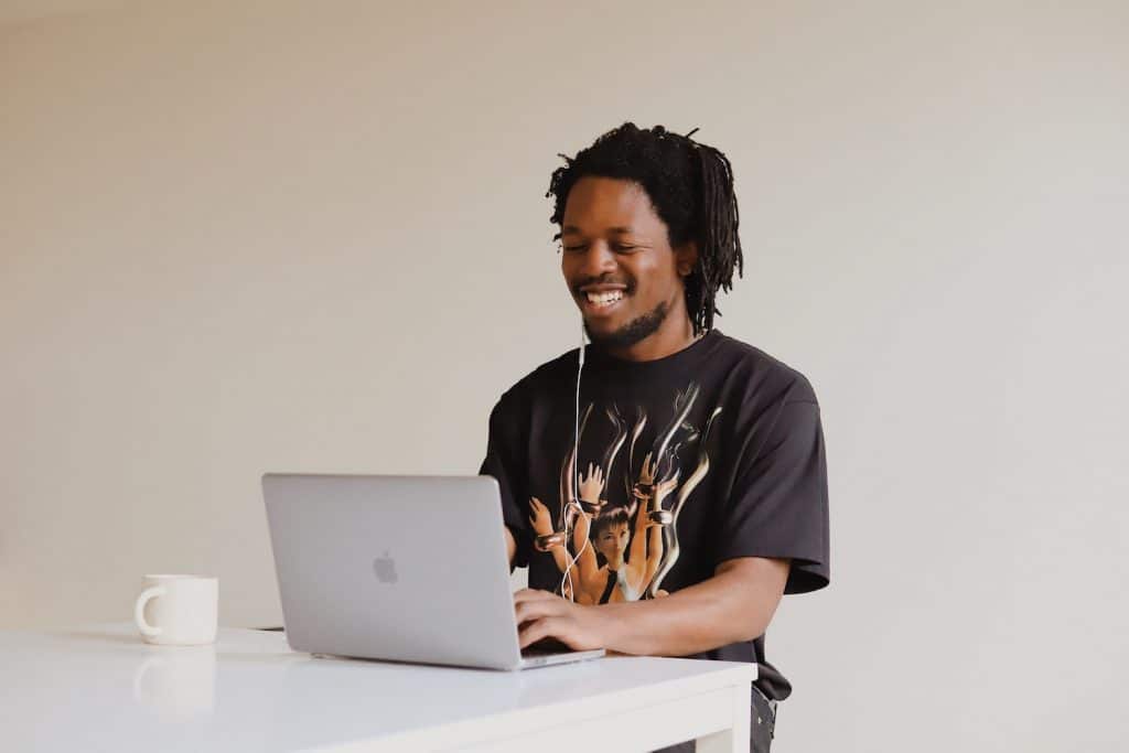 Image of a person smiling and using a laptop.