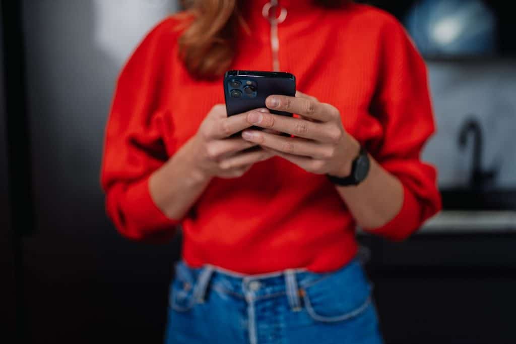a person in a red sweatshirt holding his mobile phone